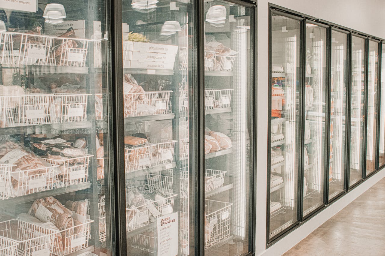 Frozen meats in a retail freezer with transparent doors and organized sections.